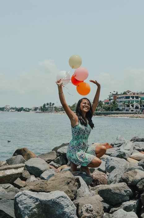 girl posing with balloons on beach