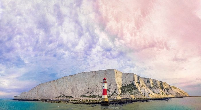 A white and red lighthouse in front of white cliffs