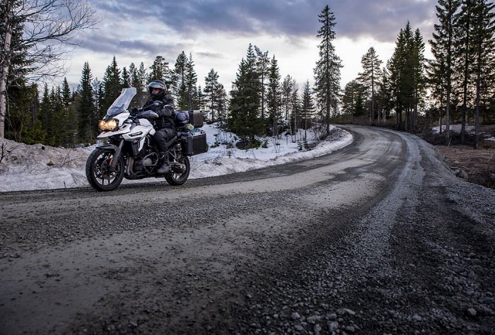 一辆摩托车在冬天行驶在林间小路上