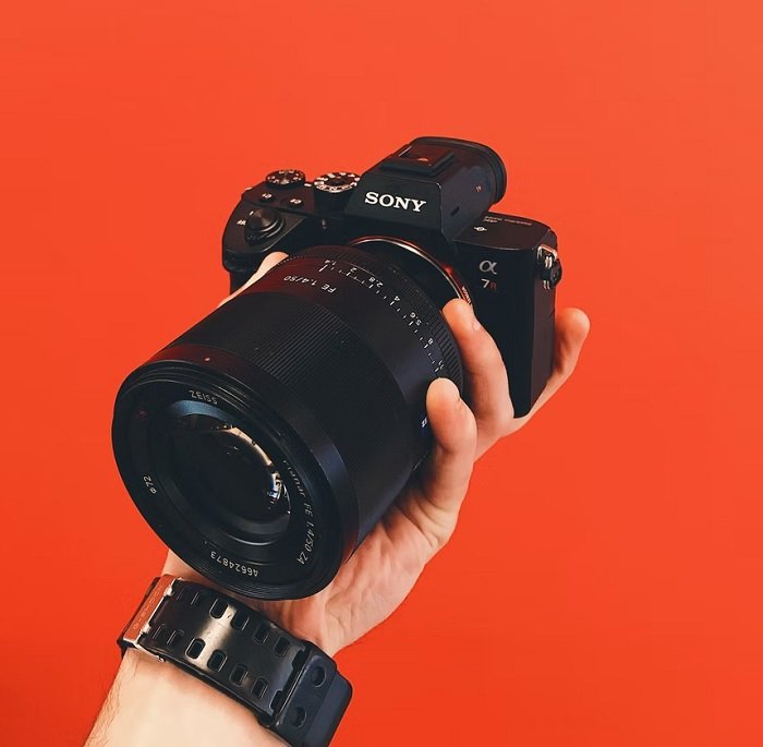 Full frame sony camera in a hand with an orange background