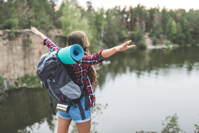 Young woman enjoying nature with her camera bag for hiking