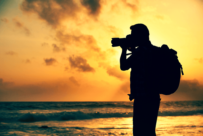 摄影师背着背包在夕阳下拍照