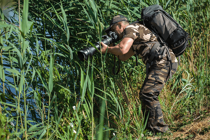 A wildlife photographer taking photos with a camera bag for hiking