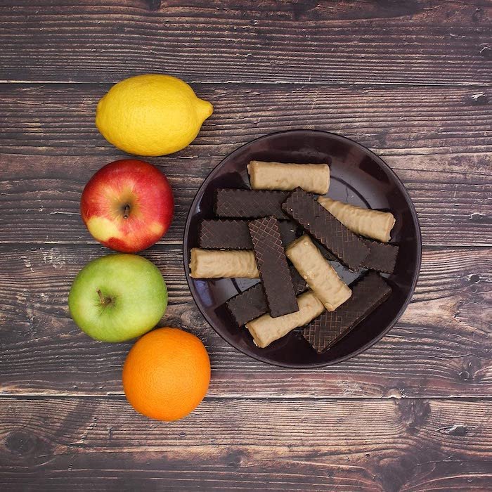 在木制背景的盘子上放着水果和巧克力棒