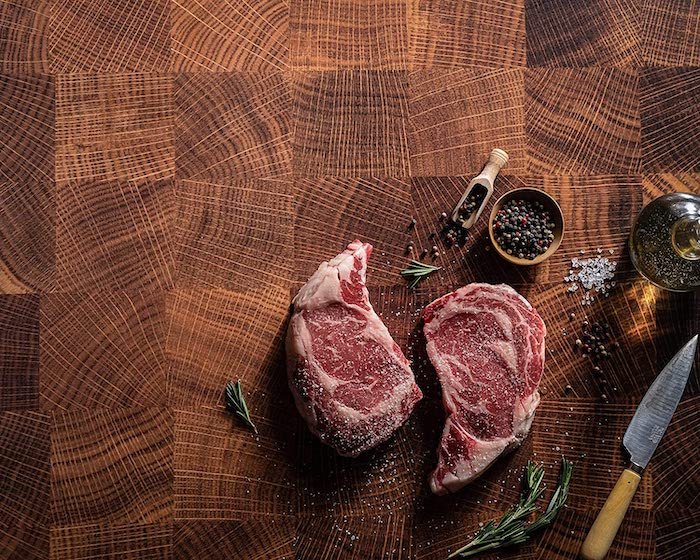 Two pieces of raw meat on a brown food photography backdrop