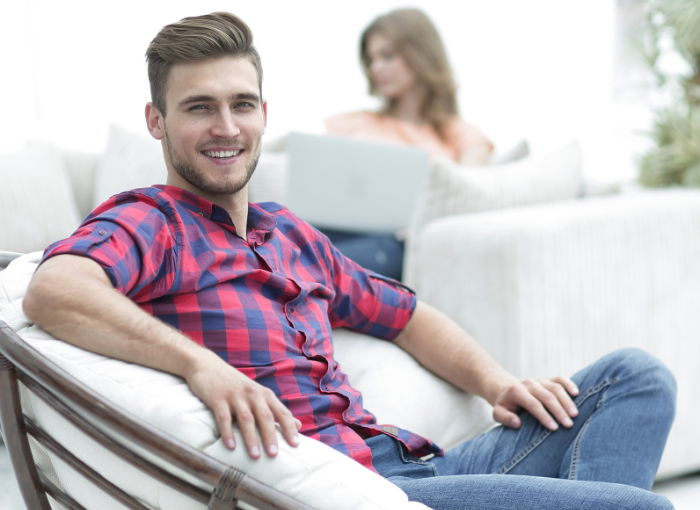 Side view of handsome young man sitting and posing on chairs in city. stock  photo - OFFSET