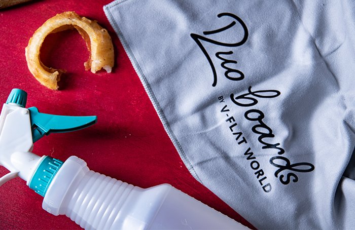 A microfiber towel and spray bottle on a Duo Board next to an onion ring