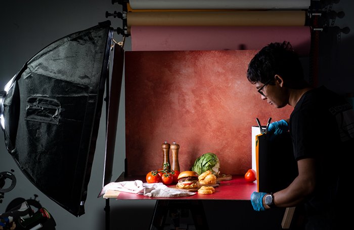 A photographing setting up lights around a food photography setup