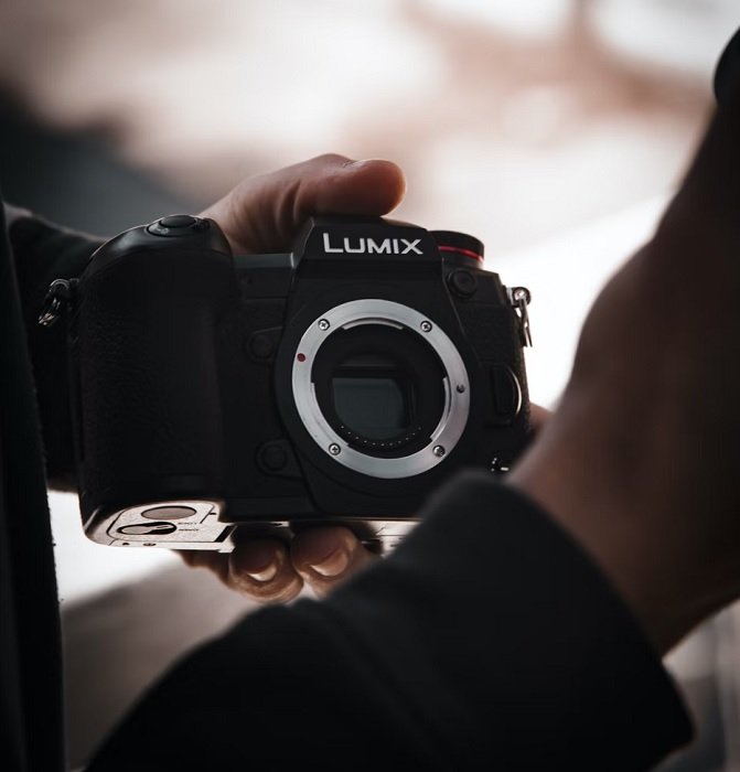 Hand holding a Lumix MFT camera with no lens attached