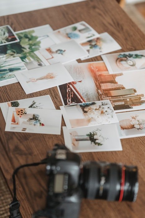 Pile of photographs on a table with a camera 