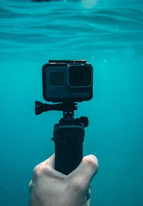 Hand holding a GoPro camera underwater