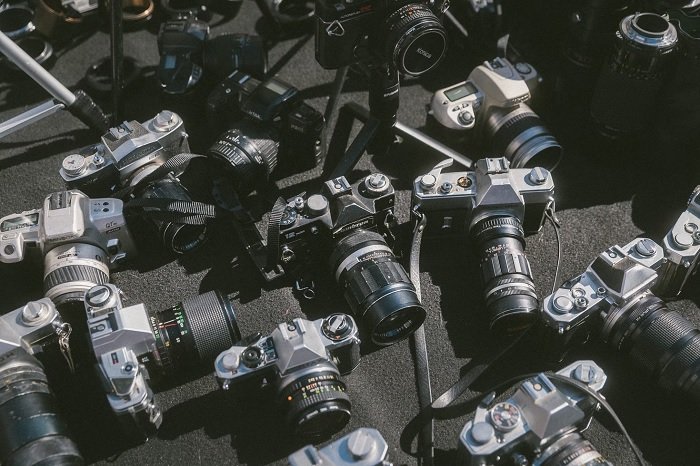 Many film cameras sitting on the ground