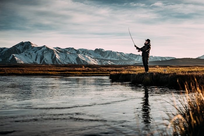 Man fishing by lake in mountain plateau