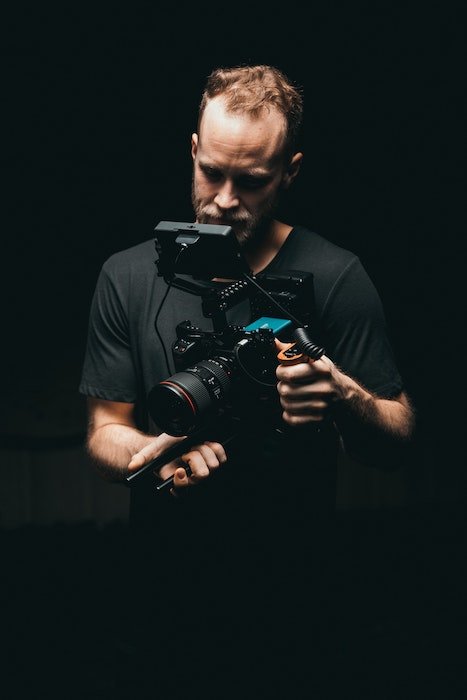 A man holding a DSLR set up to record video