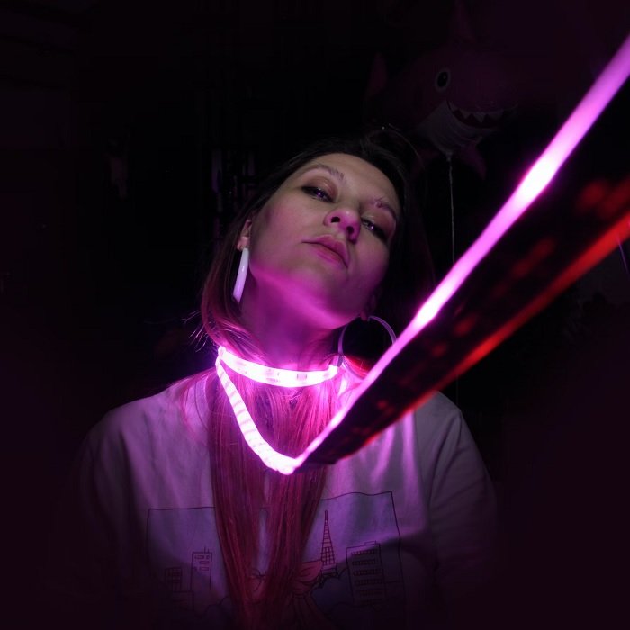 Portrait of a young woman with strip lights around her neck