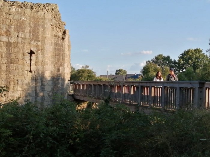 Two people walking across a bridge next to a castle