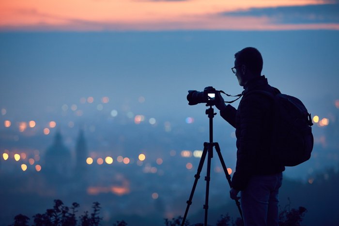 A photographer capturing a cityscape in the background