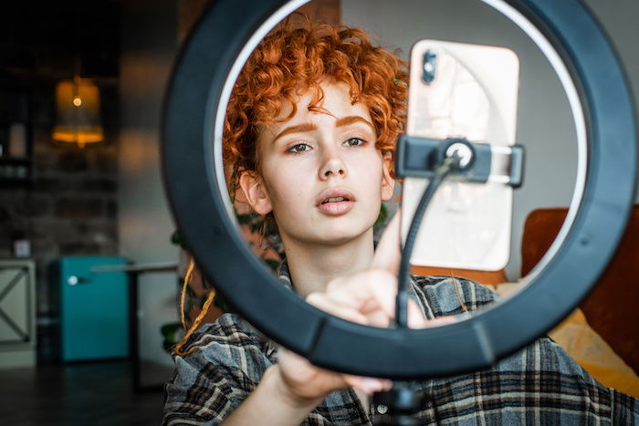 Woman setting up her smartphone in a ring light for a zoom meeting