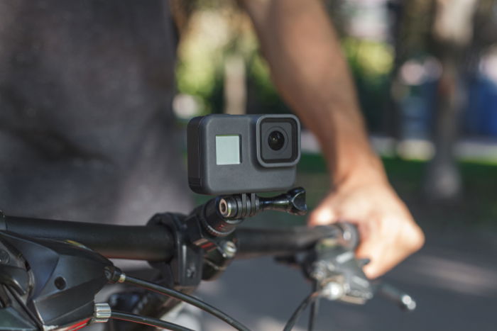 Action camera mounted on the handlebar of a bicycle that a male cyclist is holding