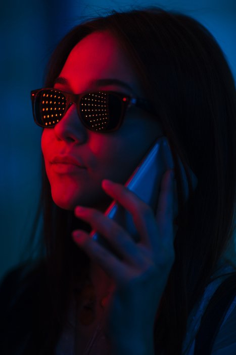 Woman with sunglasses talking on a smartphone lit by LED lights