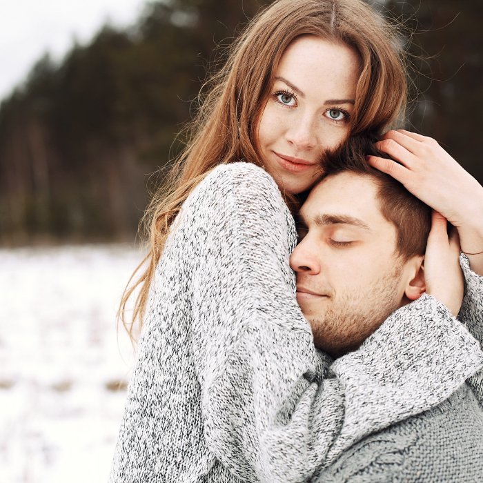 Young couple hugging against a snowy landscape