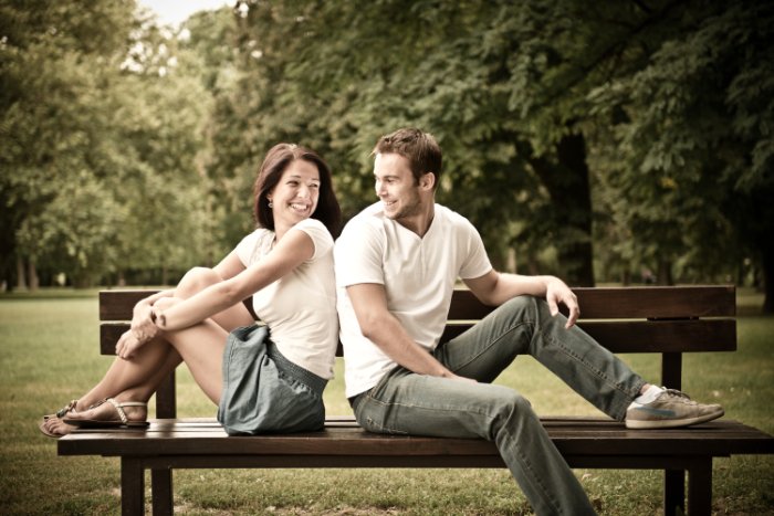 Young couple in coordiated clothes sitting smiling at each other on a bench