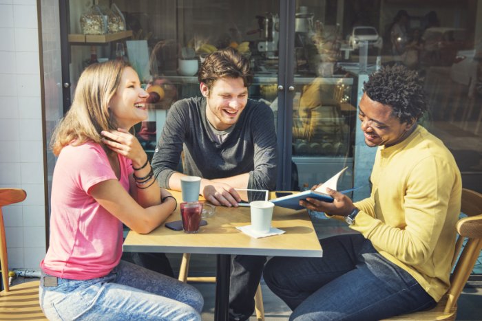 Three people meeting outside a coffee shop