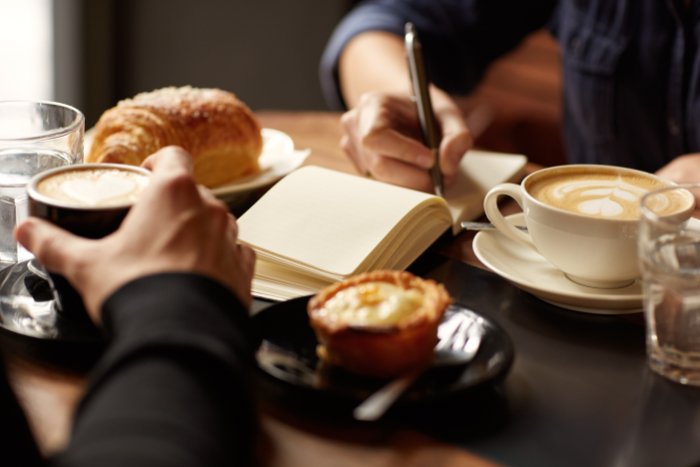 Close-up of someone writing a list in a coffee shop