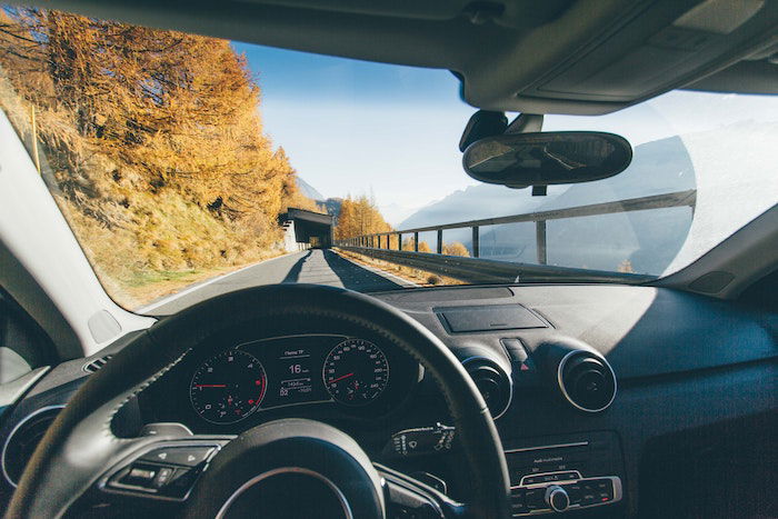 Driver's point of view of car being driving through mountains with tunnel in the distance Driver's point of view of car being driving through mountains with tunnel in the distance