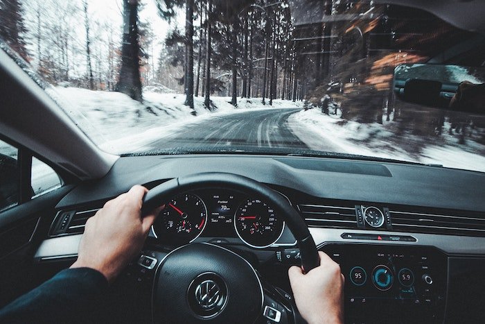 Driver's point of view of car driving on a road through a snowy landscape