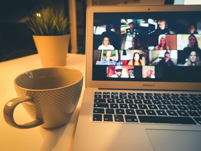 coffee cup next to a laptop with a zoom meeting