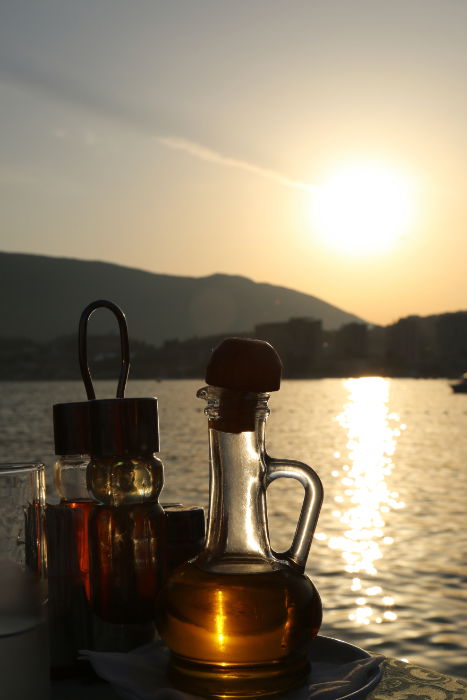 Condimentos de restaurante contra um pôr do sol sobre o mar.