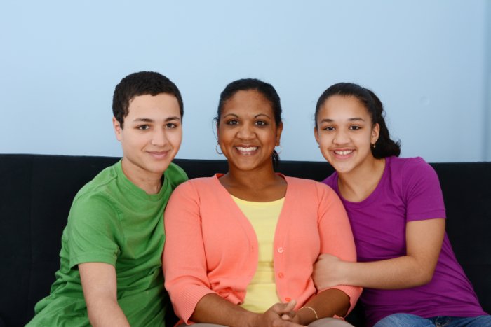 A family sitting on a couch wearing bold colors
