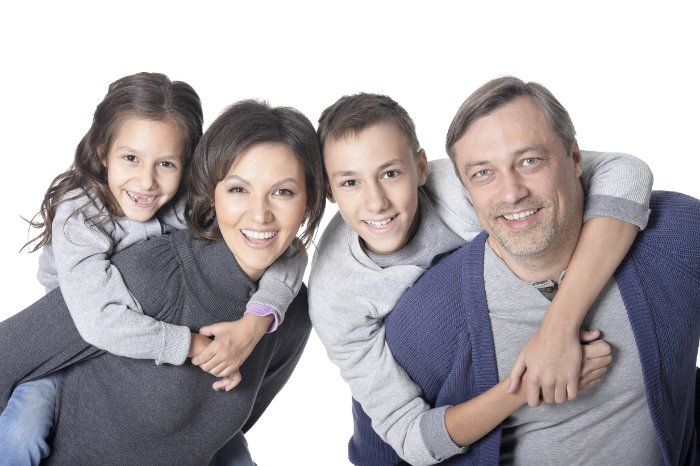 A family posing in pastel- and gray-colored clothing against a white background