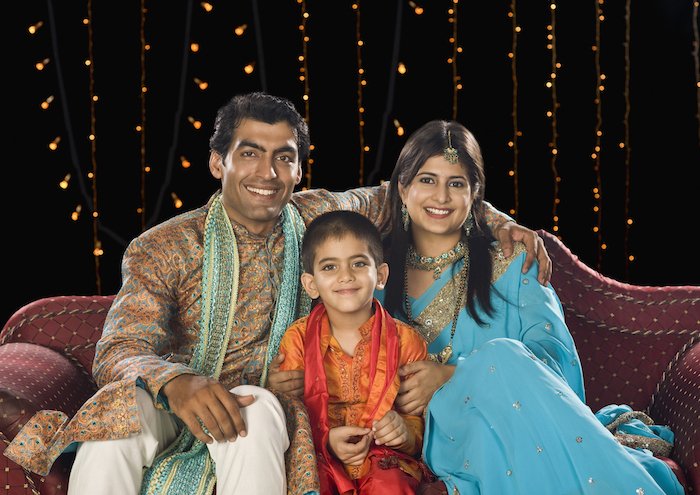 Family wearing colorful patterns and posing on a couch for Diwali festival