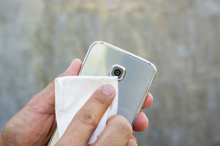 Man cleaning his smartphone with a microfiber cloth