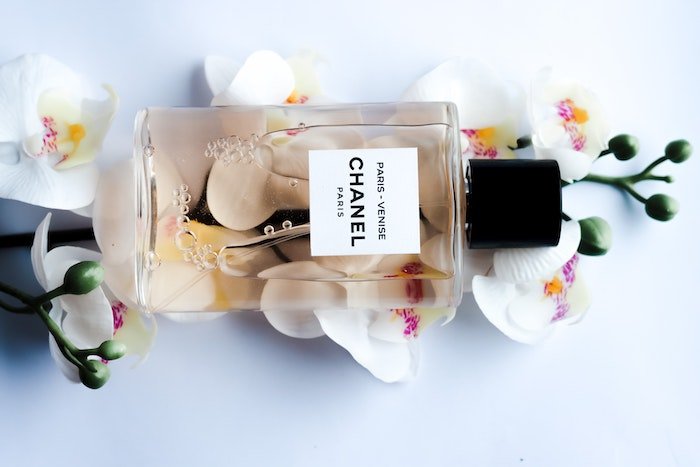 Bottle of Chanel Perfume laying sideways on orchids shot with a lens for product photography