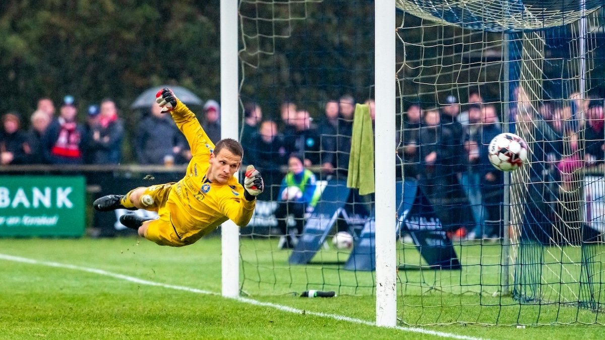 A European football goalie being scored on in a soccer game taken with a lens for sports photography
