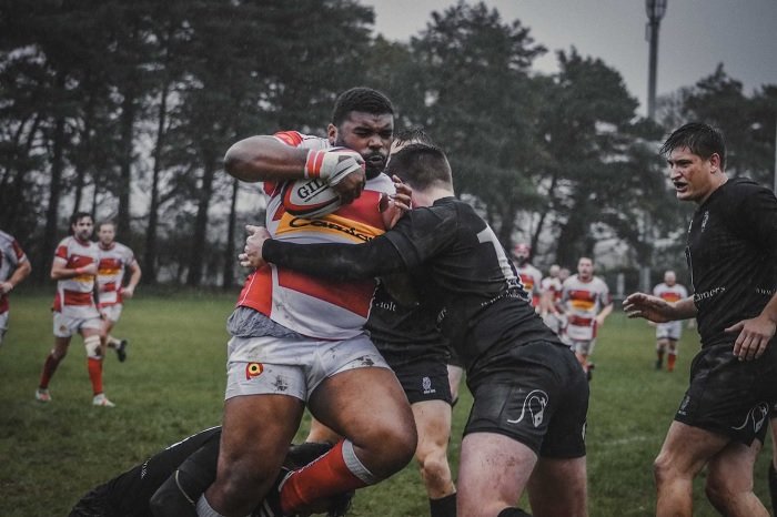 Rugby player being tackled by two rival players