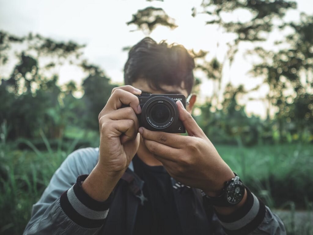 Young man holding a Panasonic Lumix compact camera for travel in a woodland area