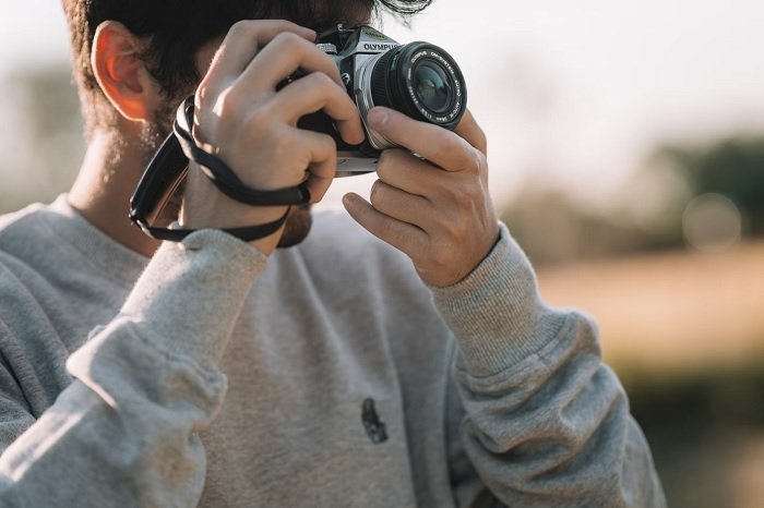 Young man in grey jumper using an Olympus Micro Four Thirds camera