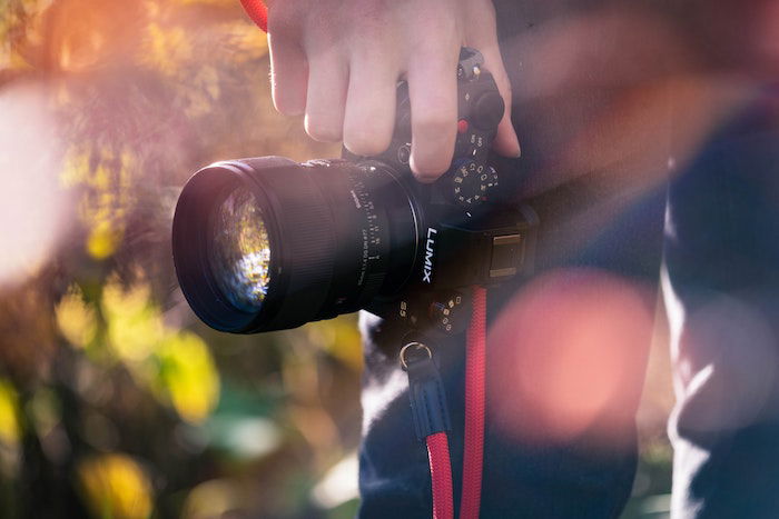 A person holding a Panasonic Lumix GH5 camera for videography