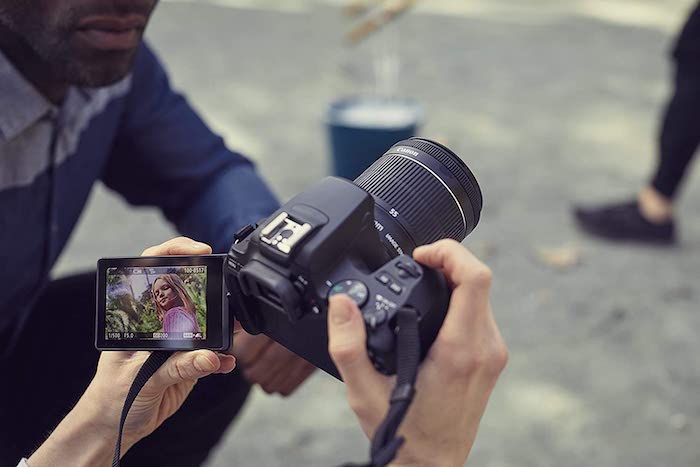 Person holding the Canon SLR3 (250D) with the flip screen open to take portrait