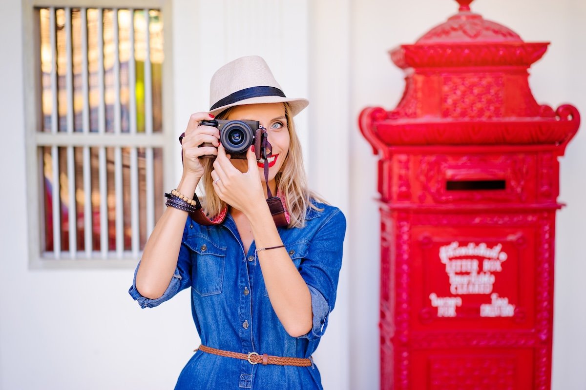 A woman in a hat holding a compact camera for travel