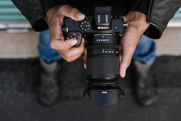 Top view of a person holding a Nikon Z lens on a mirrorless camera