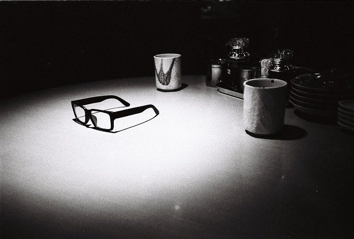 Still life of glasses and mugs on a table under a spotlight