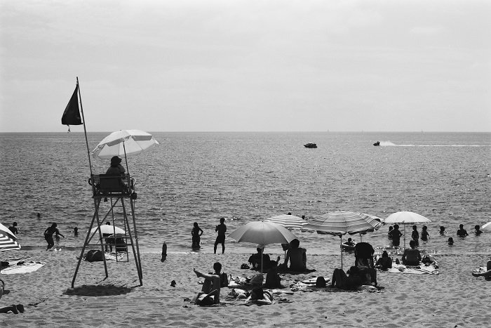 Black and white shot of sunny beach with lifeguard on a raised chair