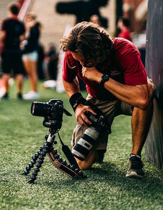 Man crouching to view a camera on a mini tripod