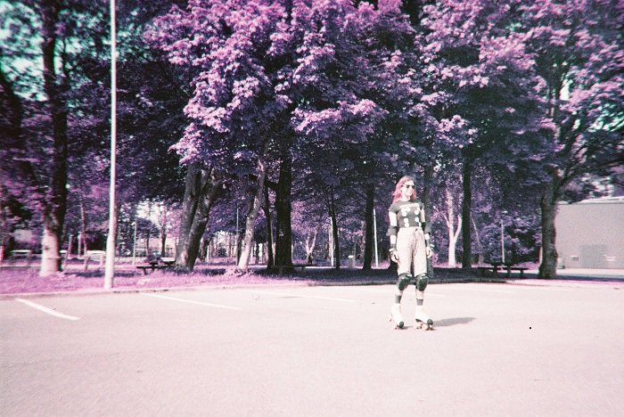 Girl on rollerblades in a park on purple film