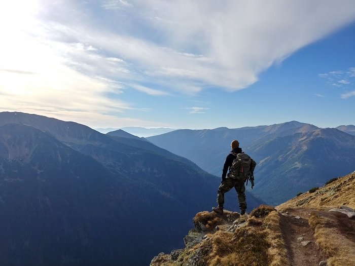 Hiker standing on a ledge looking at a mountainous view